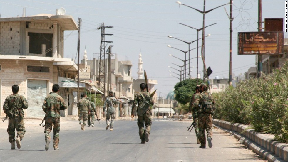 Syrian government forces walk down a street in Halfaya, Syria, after taking the city from rebel forces on Friday, September 12. 