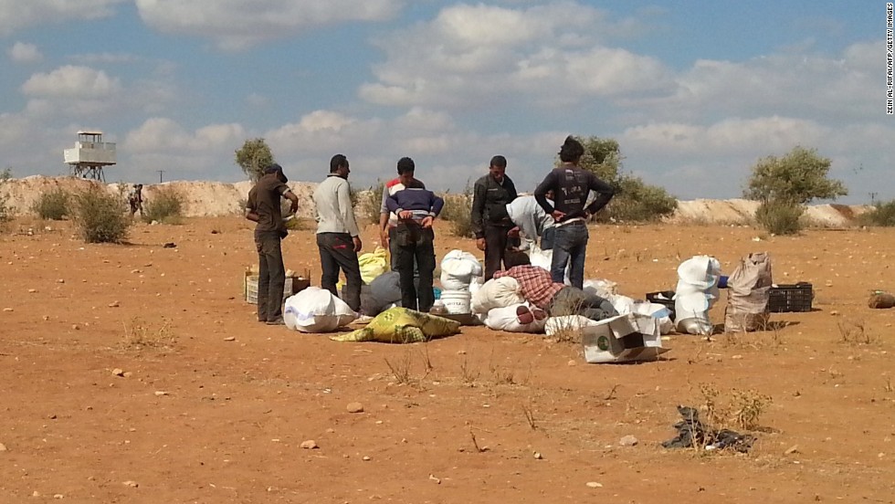 Syrians fleeing the violence stand next to their belongings as they attempt to cross into Turkey on Sunday, September 7.