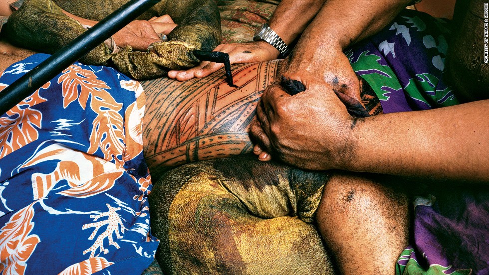 This photograph, taken by Mark Adams in 1980, captures the bloody and painful process of customary tattoo among Samoan men. It involves excruciating pain, said to be the equivalent of childbirth in women.