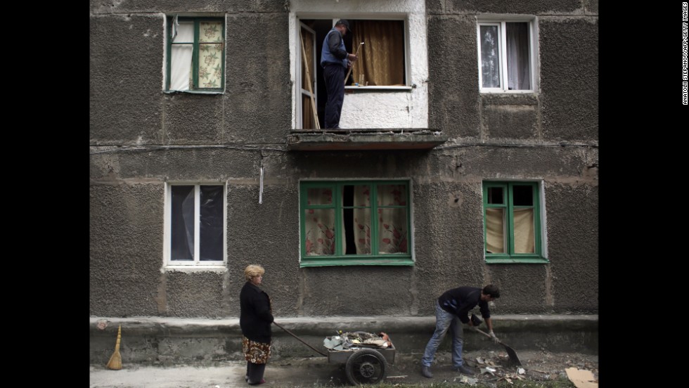 Residents clean up debris at a building damaged by rockets in Debaltseve, Ukraine, on Monday, September 22.
