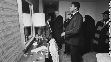 Ali looks in his hotel room mirror surrounded by members of his entourage on February 15, 1967.