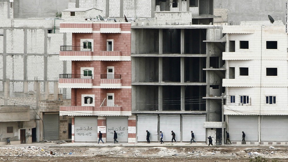 Kurdish fighters walk to positions as they combat ISIS forces in Kobani on Sunday, October 19.