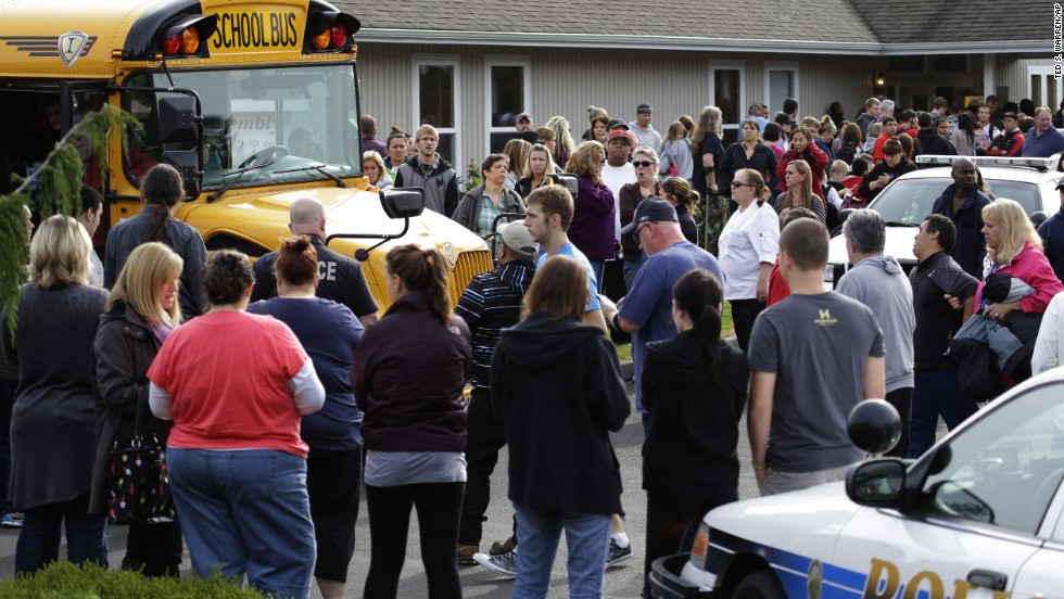 Parents crowd around buses as students arrive at the church. 