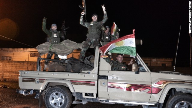 Kurdish peshmerga fighters gesture and wave a Kurdish flag from a military vehicle armed with a heavy infantry weapon as they ride towards the Syrian town of Kobane, also known as Ain al-Arab, from the border town of Suruc, in the Turkish southeastern Sanliurfa province, on October 31, 2014. 