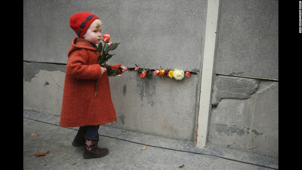 Hulda, age 3, places flowers between blocks of the former Berlin Wall.