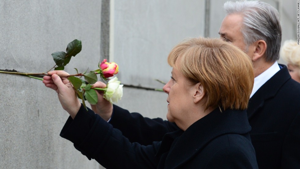 German Chancellor Angela Merkel and Berlin Mayor Klaus Wowereit place roses in the preserved segment of the wall.
