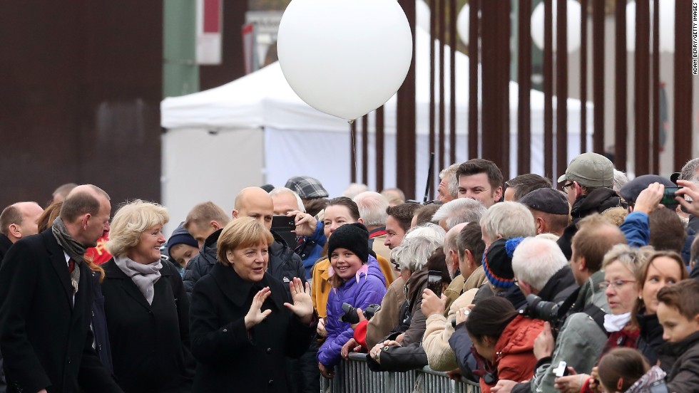 Merkel and other officials greet spectators as they walk to the Chapel of Reconciliation behind a section of the former Berlin Wall.