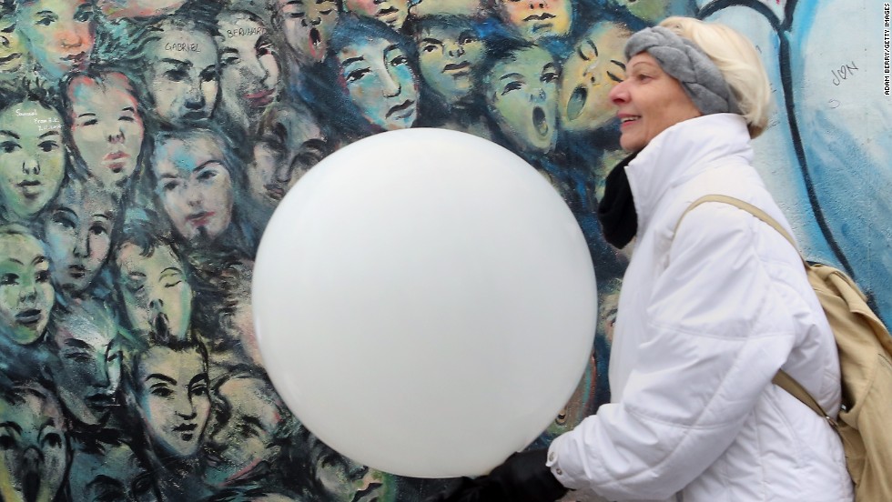 A visitor carries a balloon from the Lichtgrenze light installation.