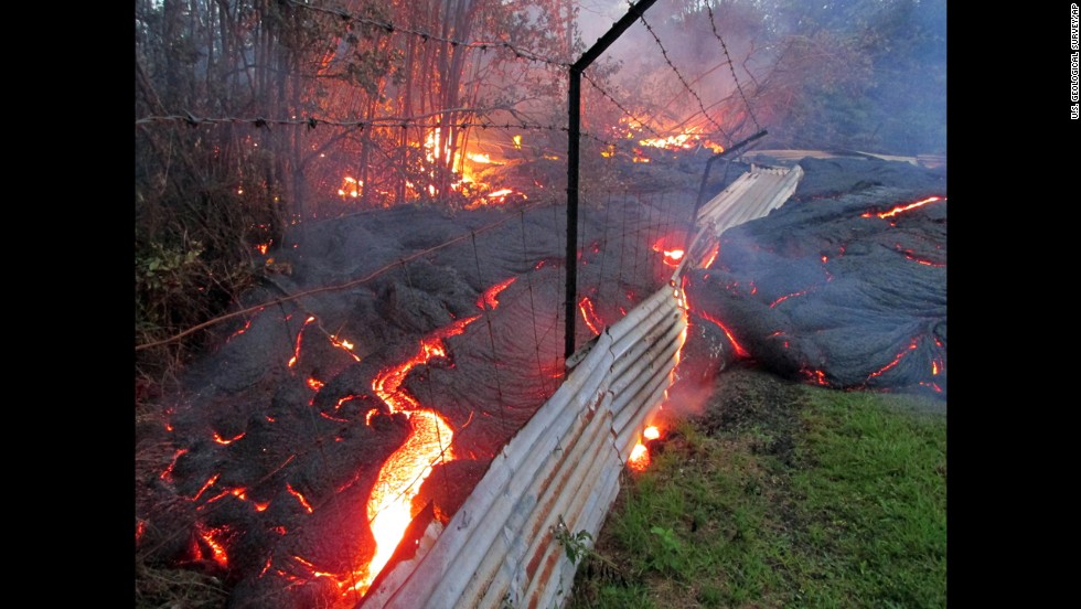 Lava flows over a fence marking a property line near the town of Pahoa on Friday, October 31. 