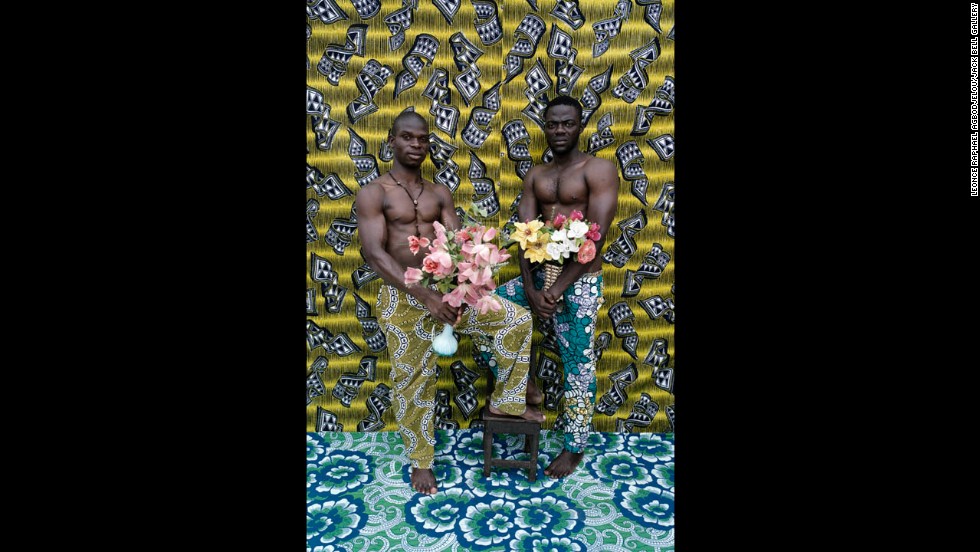 Bodybuilders pose with flowers against a colorful backdrop.