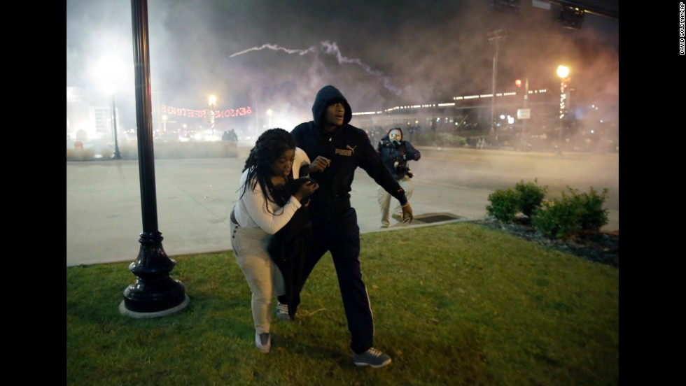 Protesters run for shelter as smoke fills the streets of Ferguson on November 24.