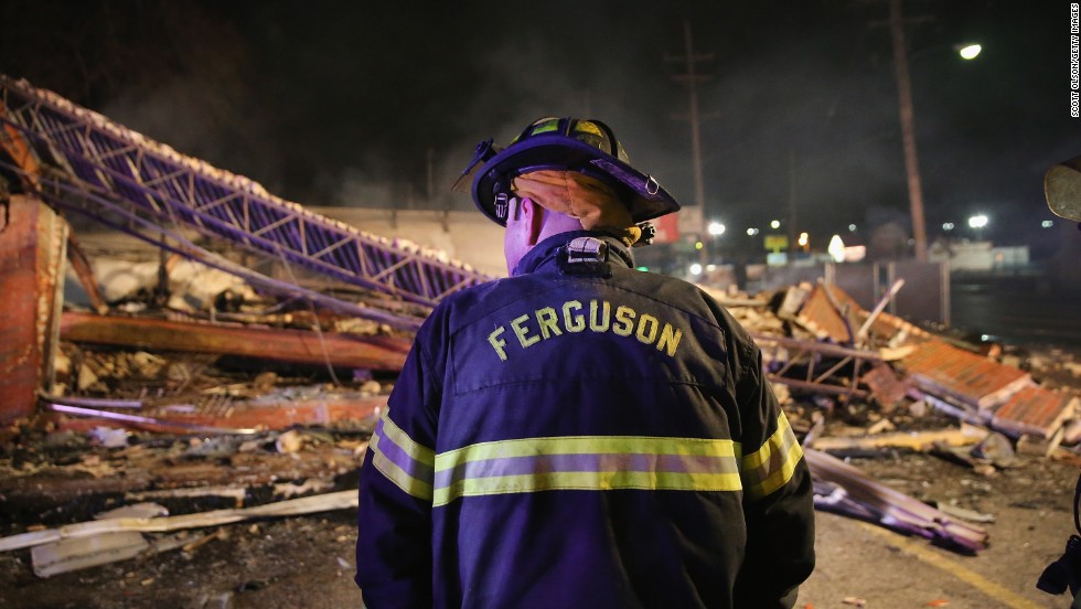 A Ferguson firefighter surveys rubble at a strip mall that was set on fire overnight.