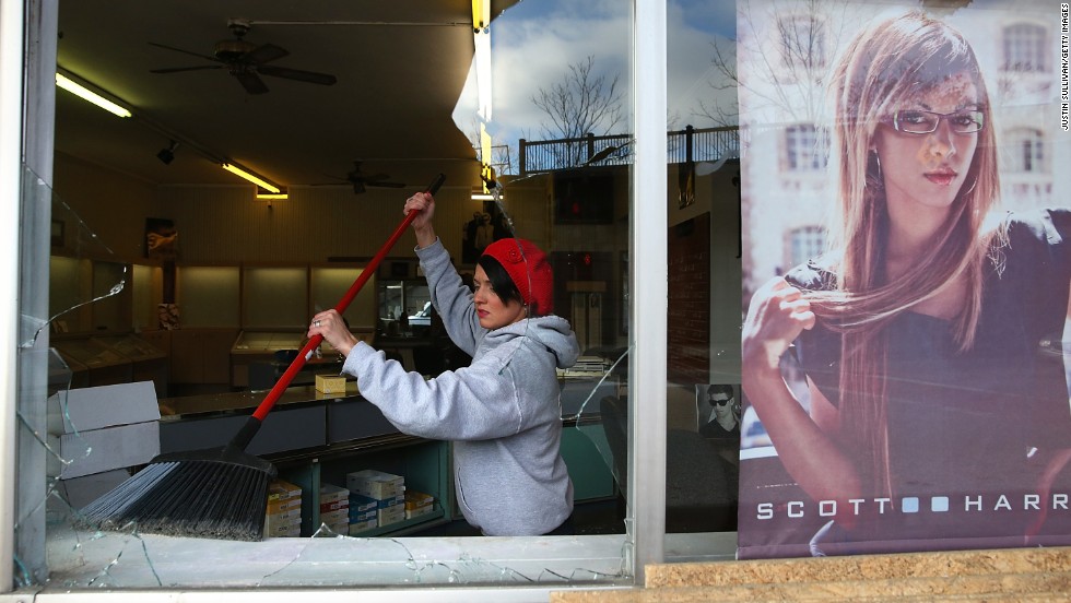 A woman cleans up glass from a business&#39; shattered window on November 25.