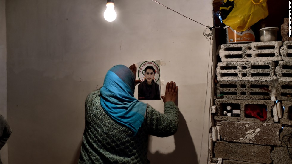 A Syrian Kurdish refugee pins a picture of her son on a wall in Suruc on Tuesday, November 11. She says he died during a battle in Kobani.