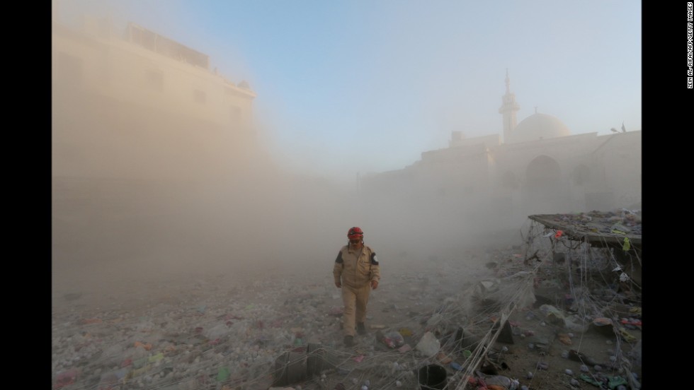 A member of the Syrian Civil Defense walks through a cloud of dust after an alleged air strike by government forces in Aleppo on November 11.