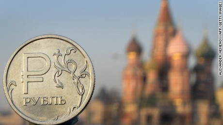 A Russian ruble coin is pictured in front of St. Basil cathedral in central Moscow, on November 20, 2014. 
