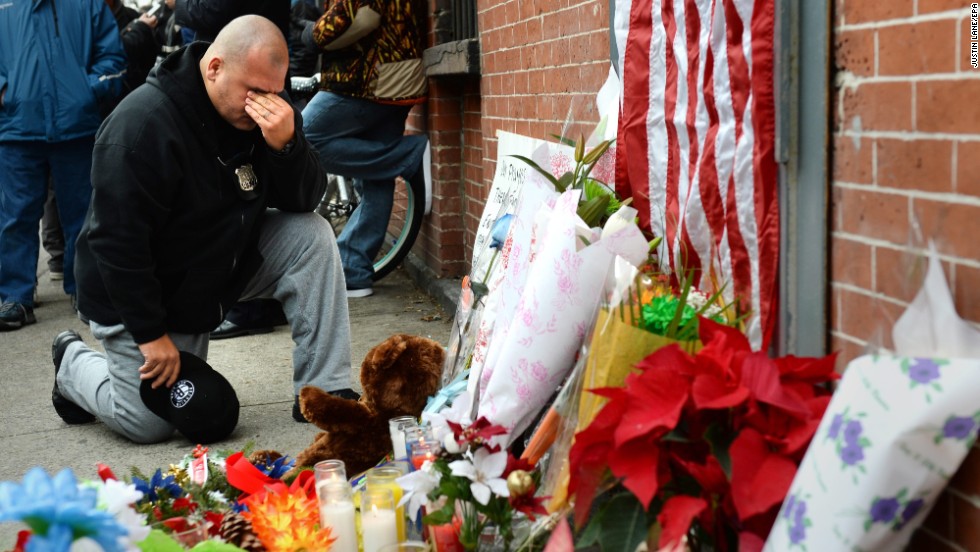 A New York City police officer kneels on Sunday, December 21, in front of a small memorial for two police officers who were killed  in Brooklyn, New York, on Saturday. 