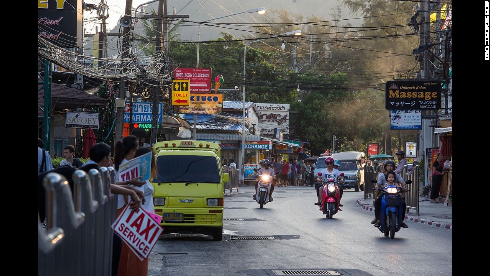 A view of Patong Beach 10 years later shows motorbikes, vans, cars and taxis traveling along a busy Patong road.