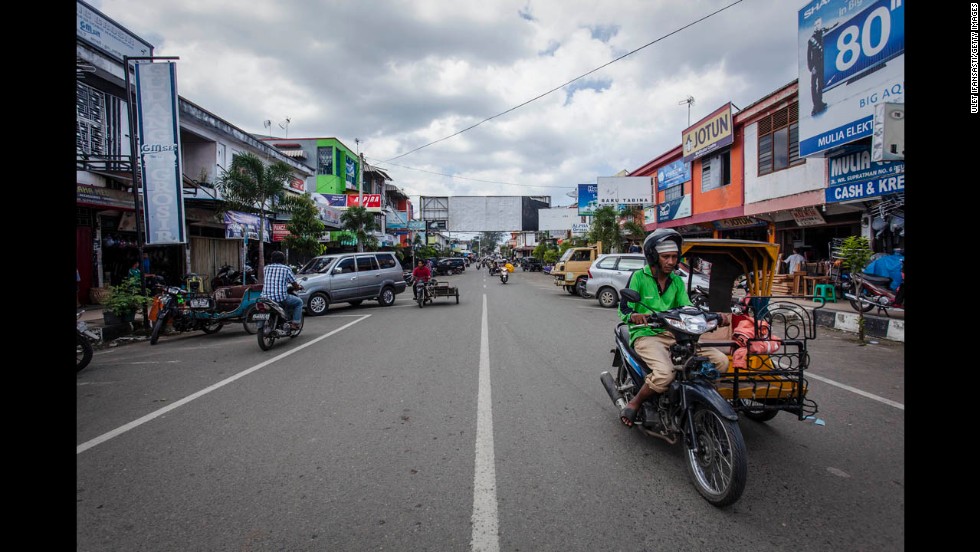 People drive along W.R. Supratman Street 10 years after the tsunami.