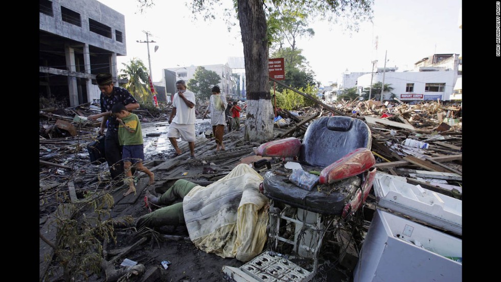 Locals in Banda Aceh walk with their faces covered as they pass bodies and debris on December 28, 2004.