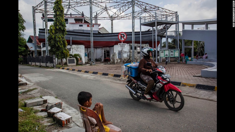 While the road has been restored, a washed-up boat still rests upon a building 10 years later.