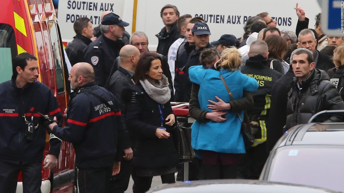 People hug each other outside the magazine&#39;s building after the attack.