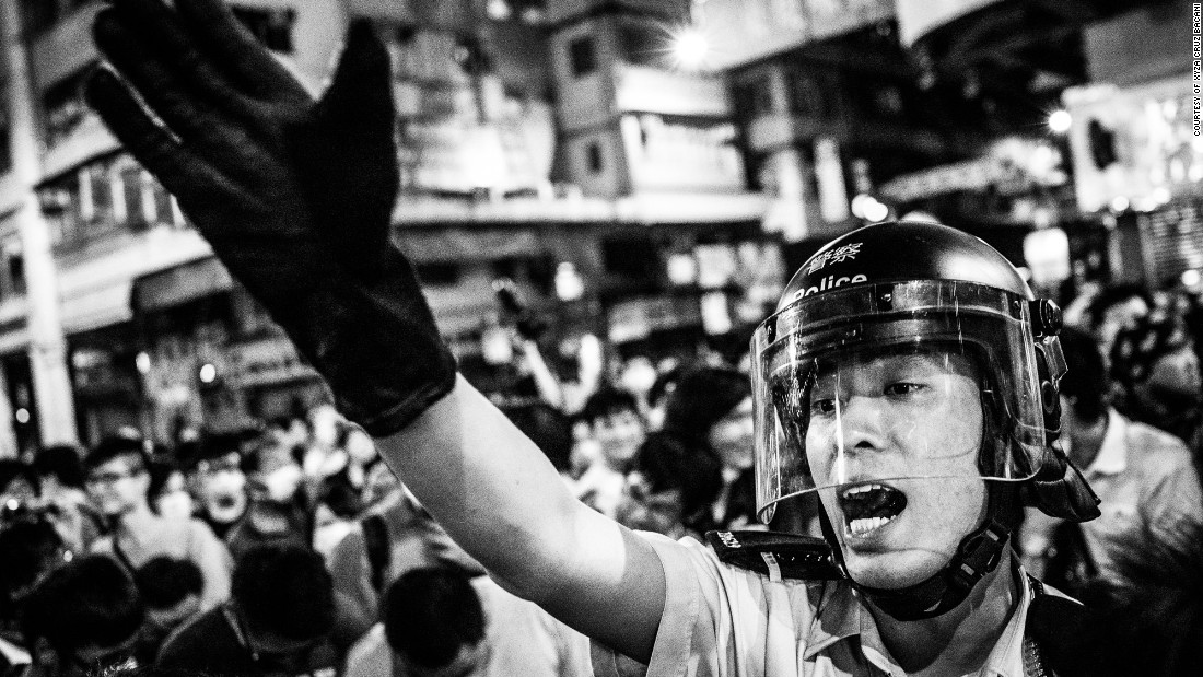 A policeman attempts to get protesters off the streets in Mong Kong, a gritty, working-class neighborhood. 