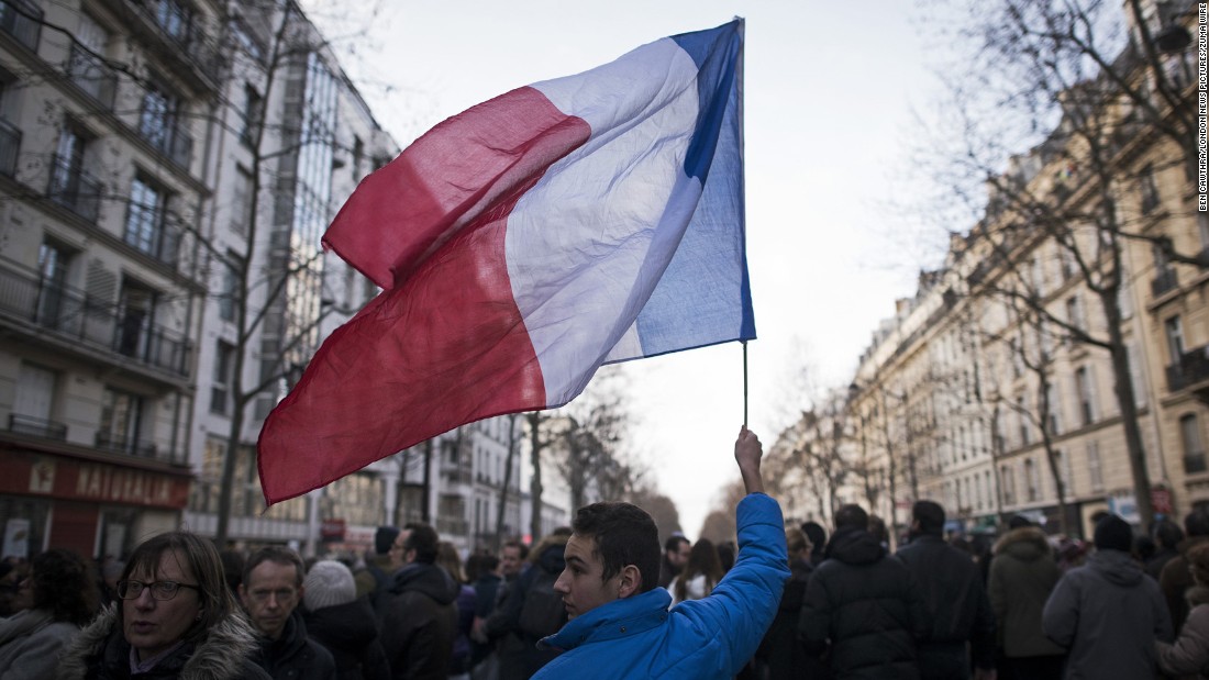 A young man waves a French national flag in the streets of Paris.
