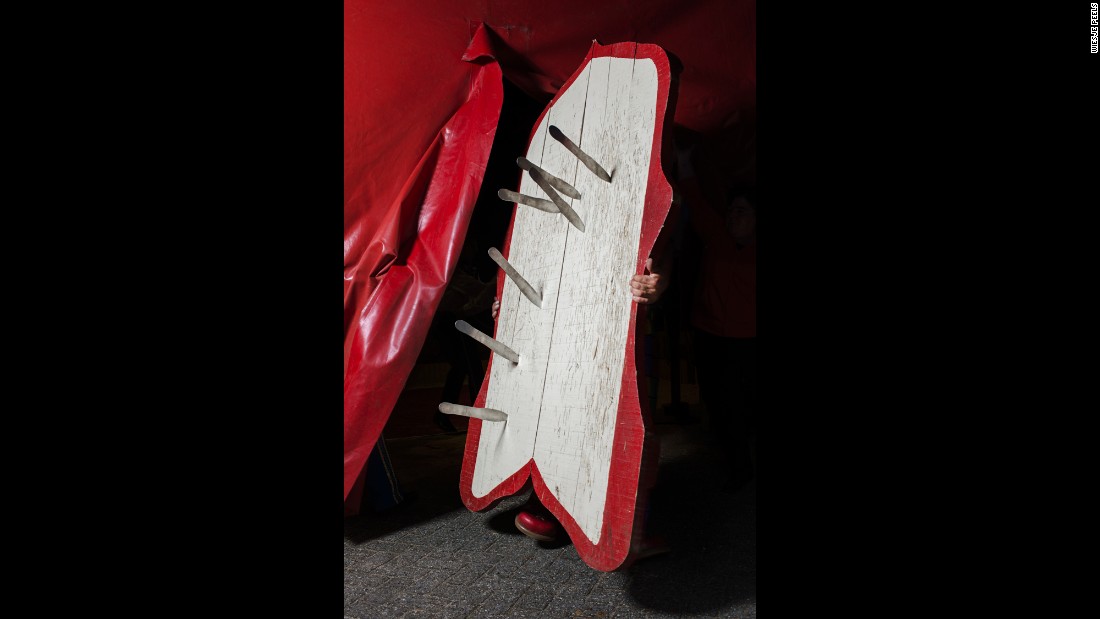 A circus performer holds a board covered with throwing knives.