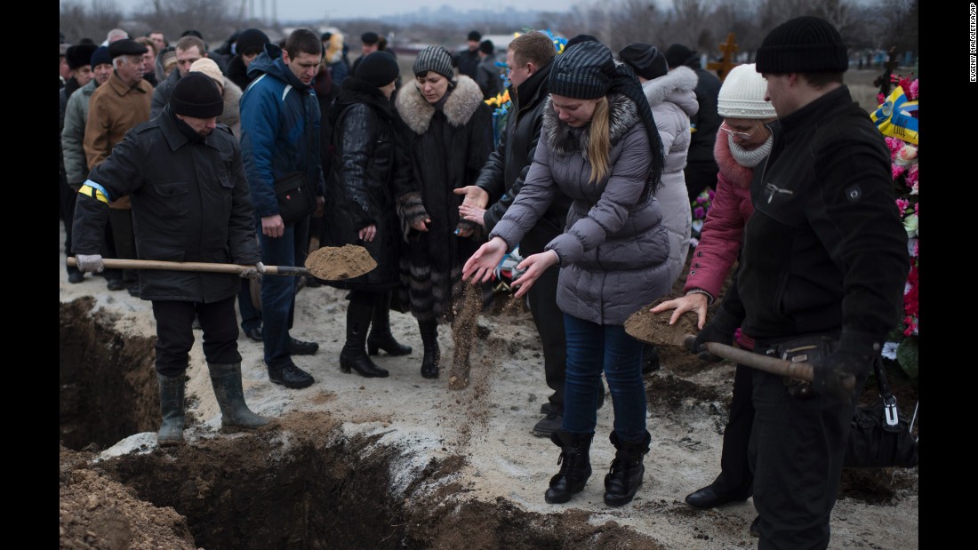 People in Mariupol, Ukraine, pour soil into the grave of a recent shelling victim on Monday, January 26. 