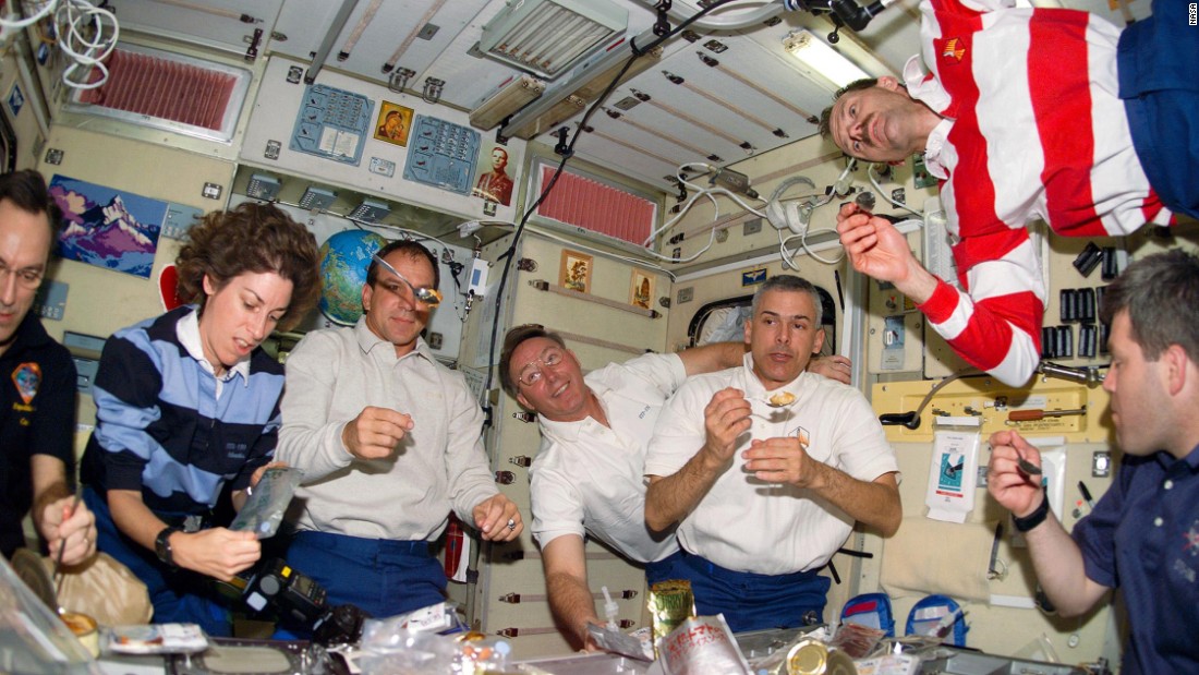 Astronauts floating around at meal time. On the International Space Station astronauts eat at a fold-down table, with food items secured with Velcro or bungee cords. But what do they actually eat?   