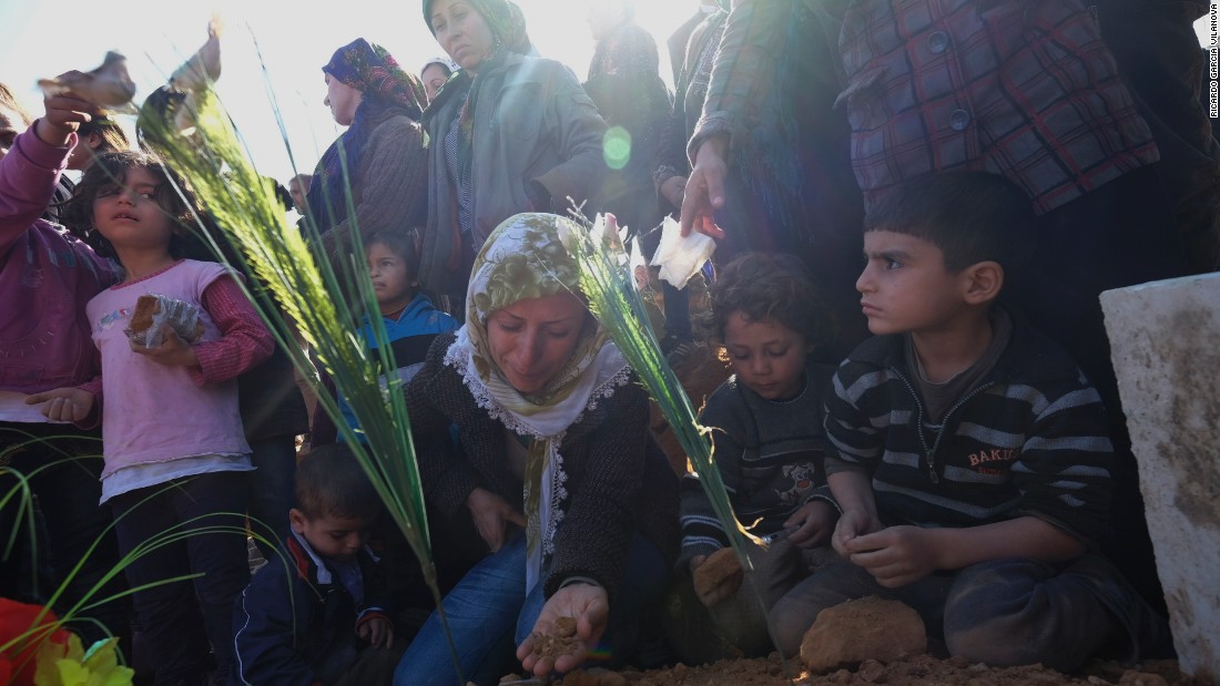 A Kurdish woman kneels beside the burial ground of her husband on Tuesday, February 3.