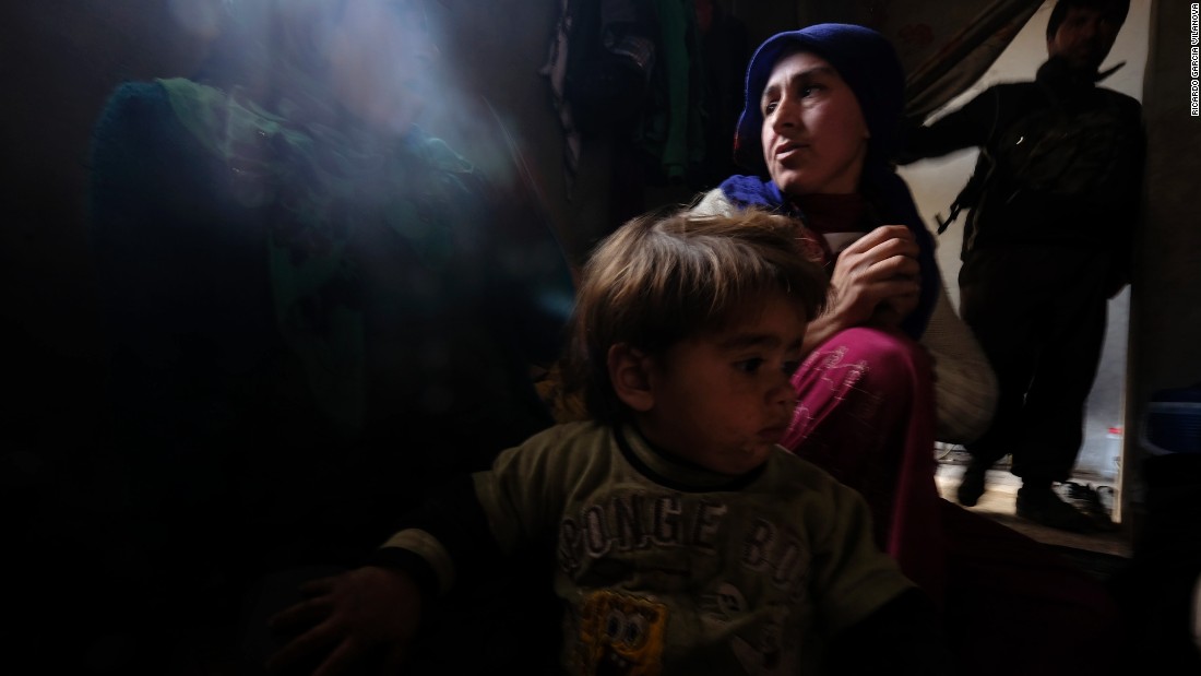 Zehra, a 25-year-old Kurdish woman who lost her 8-month-old daughter due to a lung infection at a refugee camp, sits with her other daughter inside their home in Kobani, Syria, on Thursday, January 29. Her husband, a fighter from the People&#39;s Protection Units, or YPG, stands in the background. After four months of intense fighting, Kurdish Peshmerga forces &lt;a href=&quot;http://www.cnn.com/2015/02/04/middleeast/kobani-syria-destruction/index.html&quot; target=&quot;_blank&quot;&gt;have liberated Kobani&lt;/a&gt; from the grip of the ISIS militant group. Click through to see more photos of Kobani taken recently by Ricardo Garcia Vilanova.