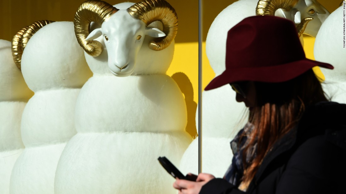 A pedestrian checks her cell phone in front of a department store in Tokyo on Friday, December 26.