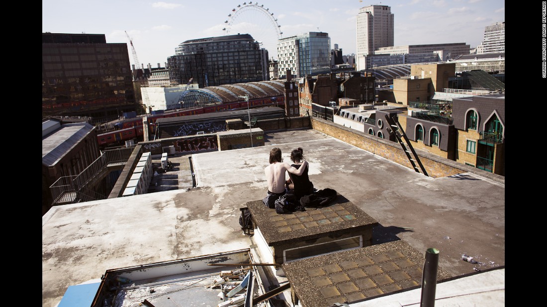 A couple sits on the rooftop of a squat in London called &quot;The Castle.&quot; Once used as a five-story office, the building has become home to more than 100 squatters -- people who don&#39;t pay rent.