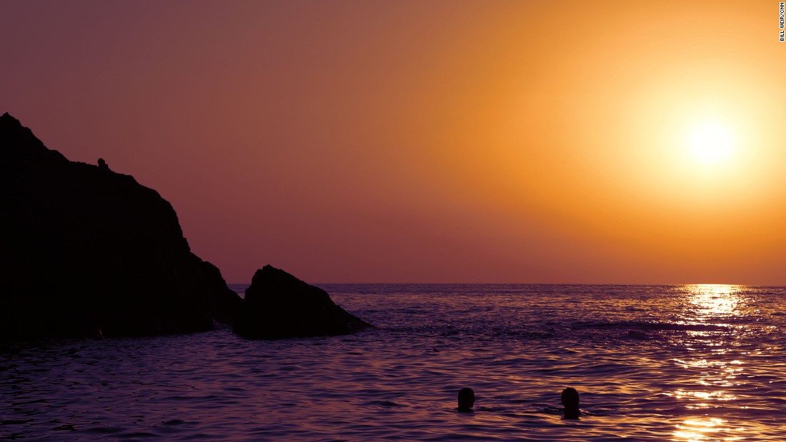 Two swimmers enjoy a sunset over Artemis&#39; Cove.
