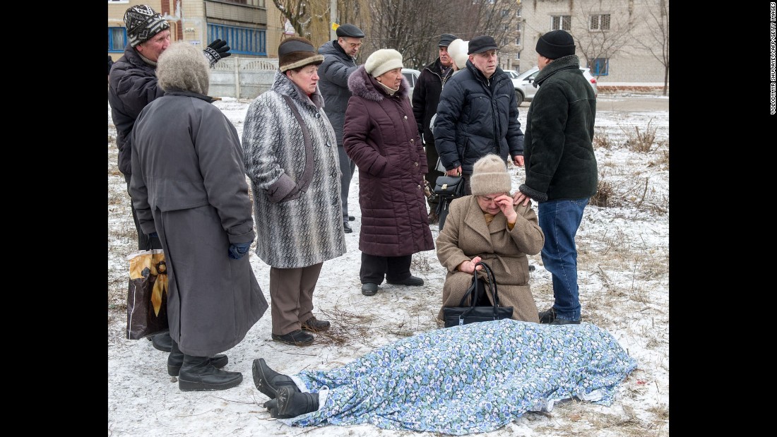 People stand beside the body of a woman killed during shelling in Kramatorsk, Ukraine, on Tuesday, February 10. 