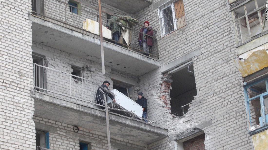 People carry a refrigerator through a balcony at an apartment building that was damaged in recent shelling in Svitlodarsk on February 15.