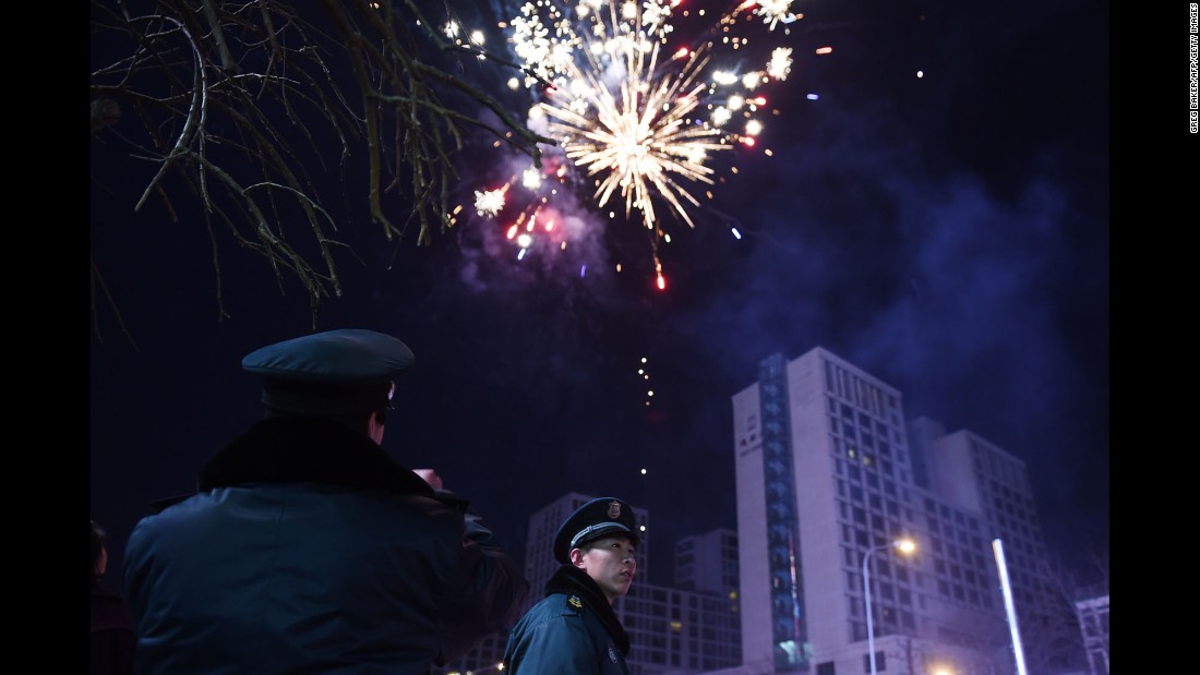 Security guards watch as fireworks go off on the eve of the Lunar New Year in Beijing on Wednesday, February 18.