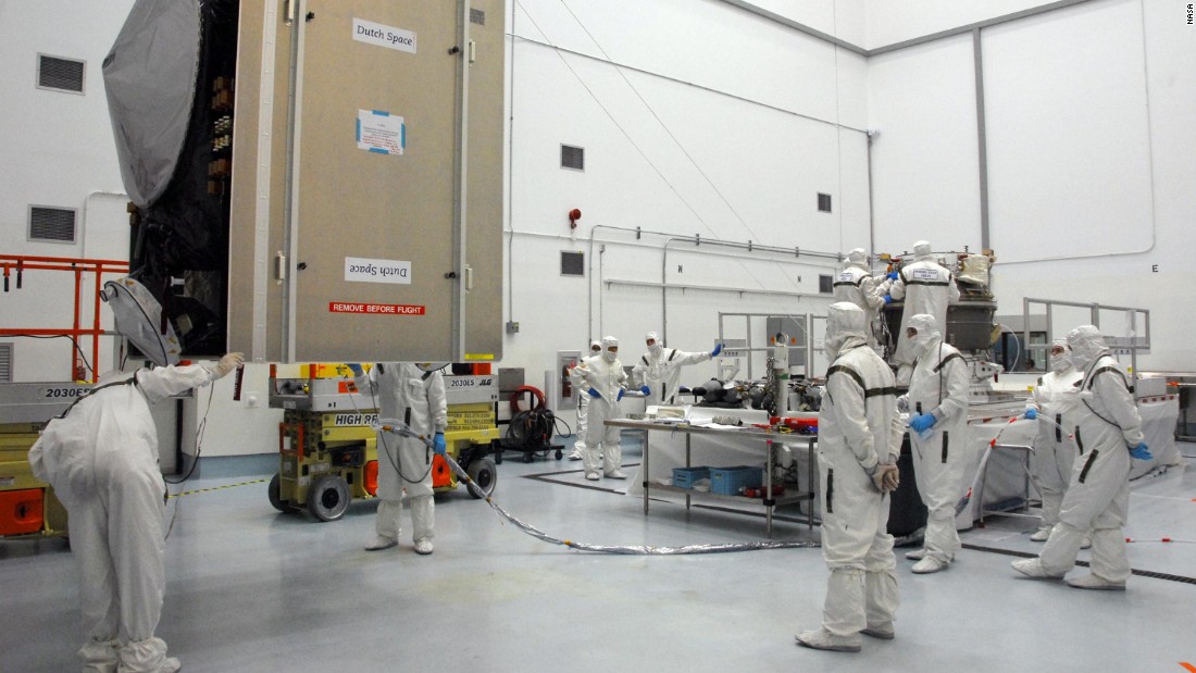 Workers check on the spacecraft, at left, as they prepare to mate it with the upper stage booster rocket on the right.