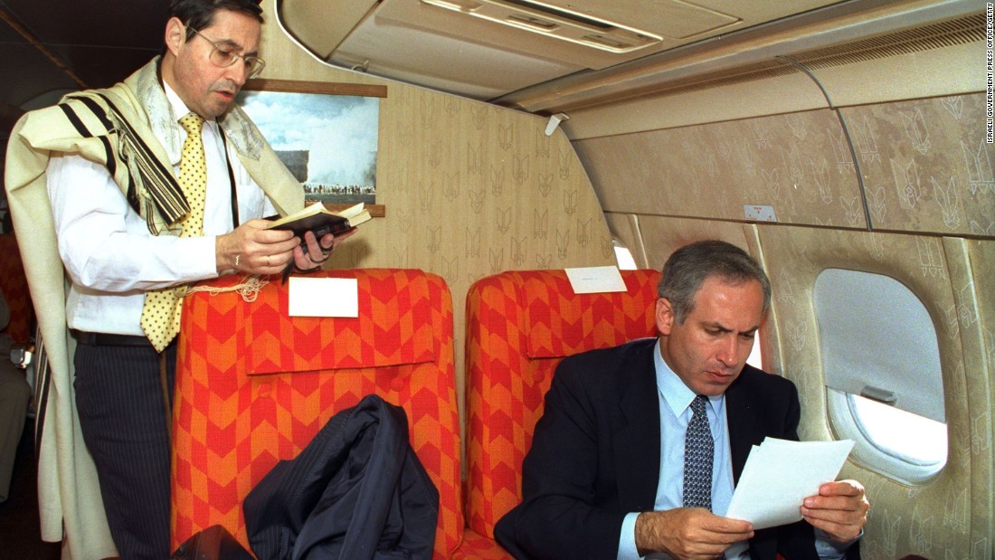 Netanyahu, as Israel&#39;s deputy foreign minister, goes through some papers as Government Secretary Elyakim Rubinstein recites morning prayers during a flight to Washington, DC, in 1989.