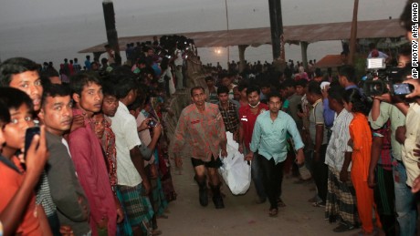 Rescue workers carry bodies after a ferry capsized after being hit by a boat on Sunday in Bangladesh.