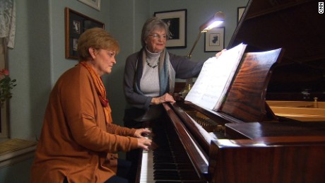 Heidi Thomas plays piano as her mother, Greta Lea Johnson, turns the pages.