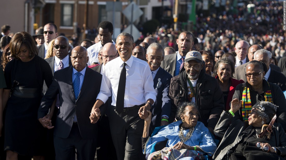 US President Barack Obama walks alongside Amelia Boynton Robinson (R), one of the original marchers, the Reverend Al Sharpton (2nd R), First Lady Michelle Obama (L), and US Representative John Lewis (2nd-L), Democrat of Georgia, and also one of the original marchers, across the Edmund Pettus Bridge to mark the 50th Anniversary of the Selma to Montgomery civil rights marches in Selma, Alabama, March 7, 2015. The event commemorates Bloody Sunday, when civil rights marchers attempting to walk to the Alabama capital of Montgomery to end voting discrimination against African Americans, clashed with police on the bridge. AFP PHOTO / SAUL LOEB (Photo credit should read SAUL LOEB/AFP/Getty Images)