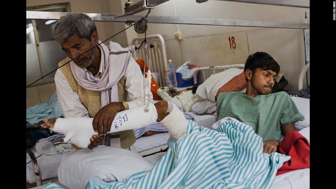 Dharmender&#39;s father, Mahaveer, helps him to move on the bed a few days after his operation.