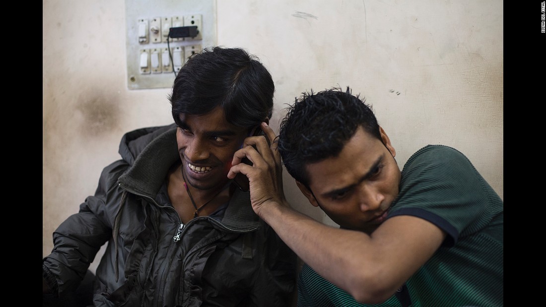 A friend holds a cell phone to Kumar&#39;s ear as he talks to his mother in November.