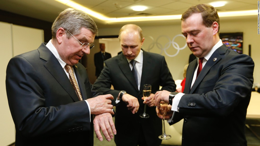 From left, International Olympic Committee President Thomas Bach, Putin and Medvedev look at their watches before the closing ceremony of the Winter Olympics in February 2014.