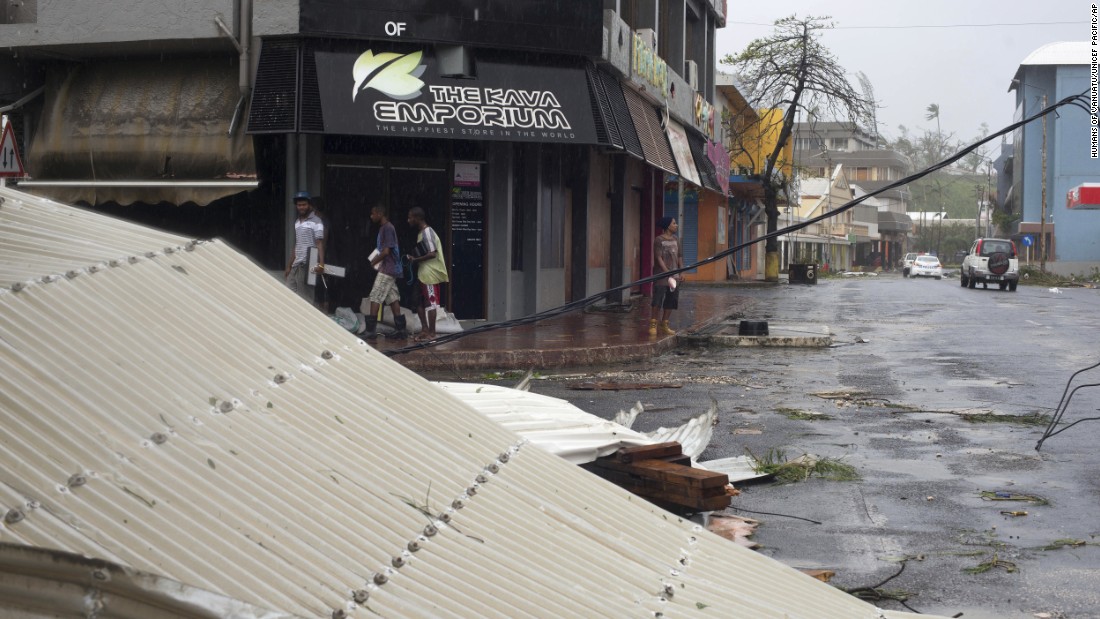 People walk past debris scattered on a street in Port Vila, Vanuatu, on Saturday, March 14. 