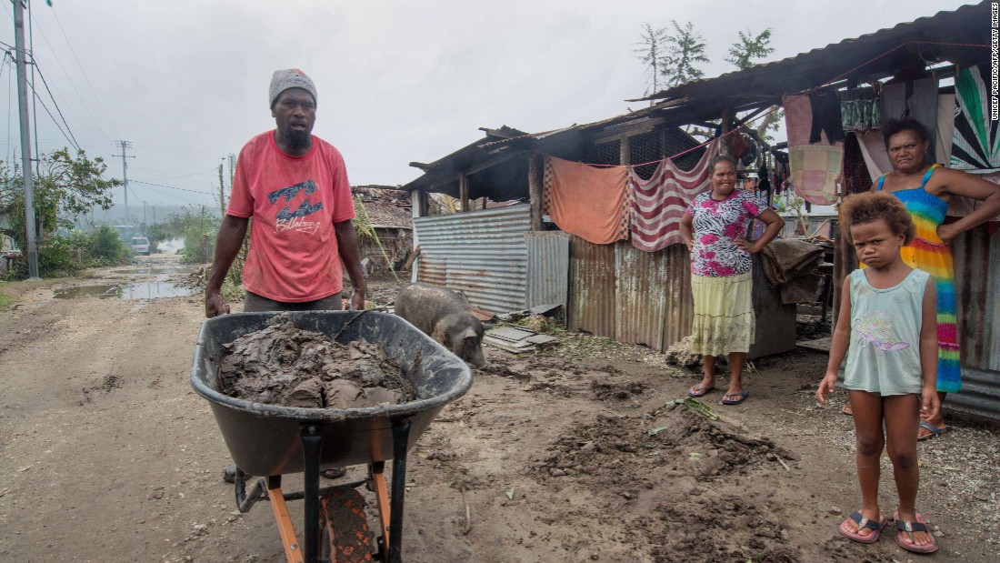 A resident clears mud and other debris outside homes near Port Vila  on March 15. 