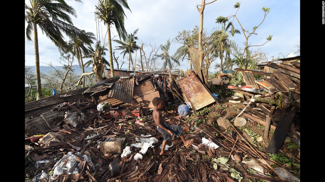 A boy kicks a ball through the ruins of his family home as his father picks through debris on March 16. 